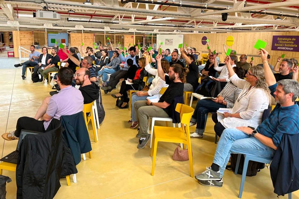 Persones participants en una sessió grupal aixecant targetes de colors durant una votació.