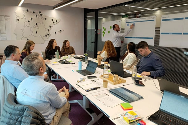 Grup de persones en una sessió de treball participativa, amb un facilitador recollint aportacions en notes autoadhesives.